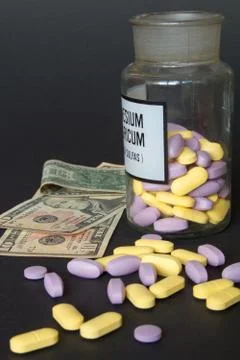 Multicolored pills in flasks on a black background. Stock Photos