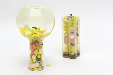 Multicolored pills or tablets in upside-down yellow glass lab flask and tes.. Foto stock