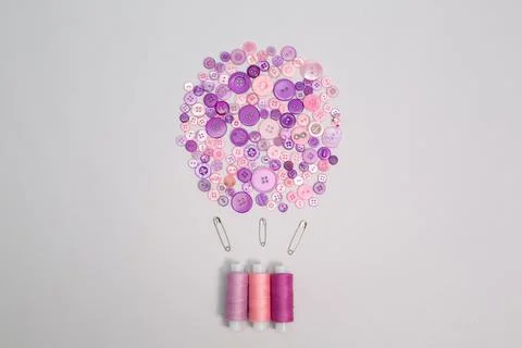 Multicolored pink thread spools and buttons on white background. Air balloon Stock Photos