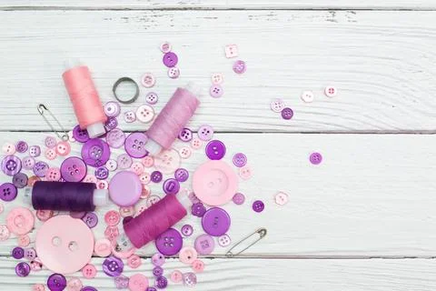 Multicolored pink thread spools and buttons on white background Stock Photos
