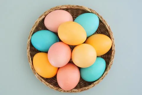 Multicolored plain Easter eggs in a basket on a light blue background. Flat lay Fotos Stock
