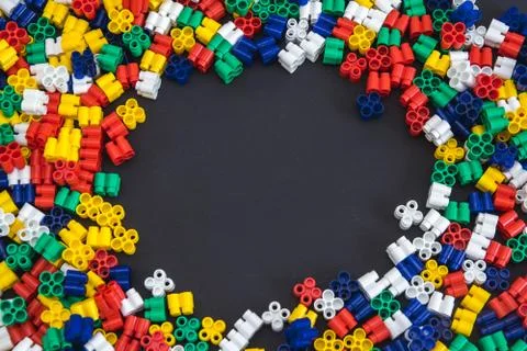 Multicolored plastic blocks on a black background with a place for text. Part Stock Photos