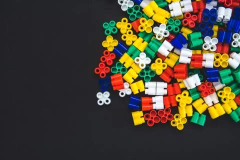 Multicolored plastic blocks on a black background with a place for text. Part Stock Photos