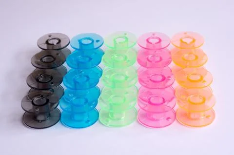 Multicolored plastic bobbin for sewing machine. layed in rows in .white backg Stock Photos