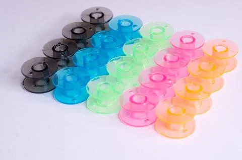 Multicolored plastic bobbin for sewing machine. layed in rows in .white backg Stock Photos