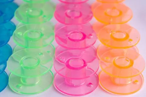 Multicolored plastic bobbin for sewing machine. layed in rows in .white backg Stock Photos