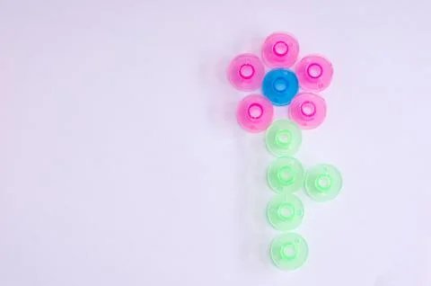Multicolored plastic bobbin for sewing machine. in shape of a flower in .whit Stock Photos