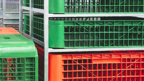 Multicolored plastic crates are stacked in a distribution warehouse. Delivery Stock Photos