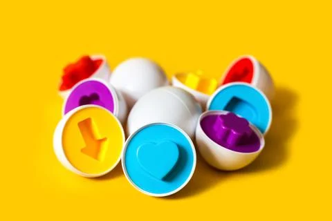 Multicolored plastic eggs on yellow background. An educational sorter toy for Фото