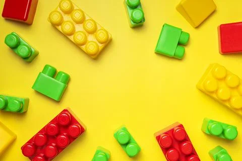 Multicolored plastic kids constructor on yellow background. Flat lay top view Stock Photos