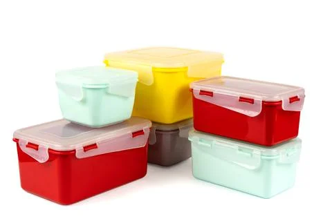 Multicolored plastic lunch boxes folded at corner on white background Stock Photos
