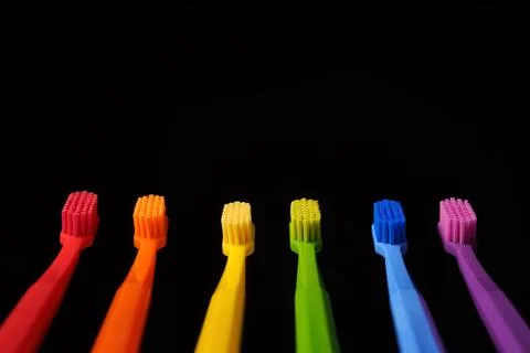 Multicolored plastic toothbrushes on a black background. Stock Photos