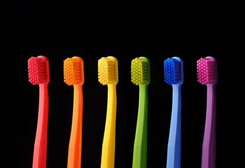 Multicolored plastic toothbrushes on a black background. Stock Photos