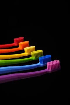 Multicolored plastic toothbrushes on a black background. Stock Photos