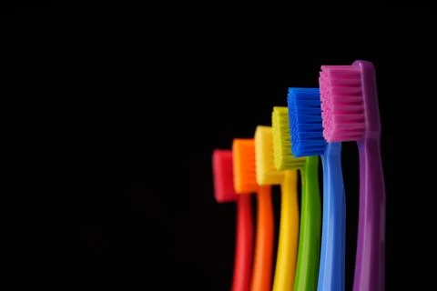 Multicolored plastic toothbrushes on a black background. Stock Photos