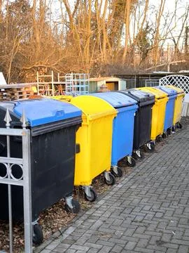 Multicolored plastic waste sorting containers lined up in a yard 스톡 사진