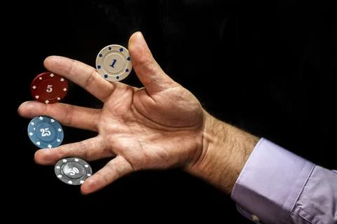 Multicolored poker chips with numbers between fingers of male hand Photos