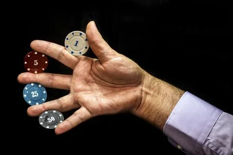 Multicolored poker chips with numbers between fingers of male hand 스톡 사진