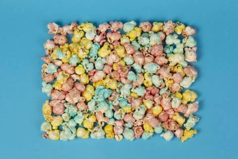 Multicolored popcorn in the shape of a square on a blue background. Colorful  Stock Photos