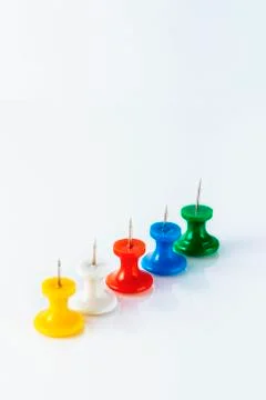 Multicolored push pins on white background. Close-up. Stock Photos