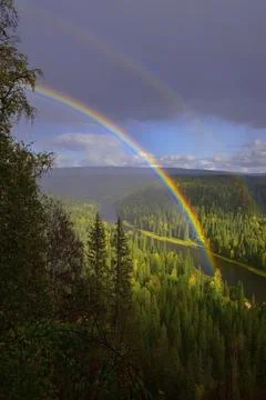 A multicolored rainbow over the autumn Ural forests and the Usva River near t Stock Photos