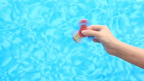 A multicolored, red-yellow-blue hand spinner or spinner, rotating on the person Stock Footage 76913475