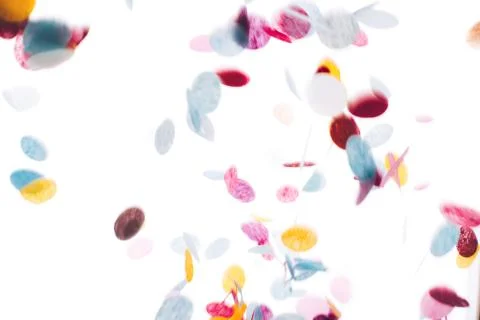 Multicolored round confetti is flying to the table. Stock Photos
