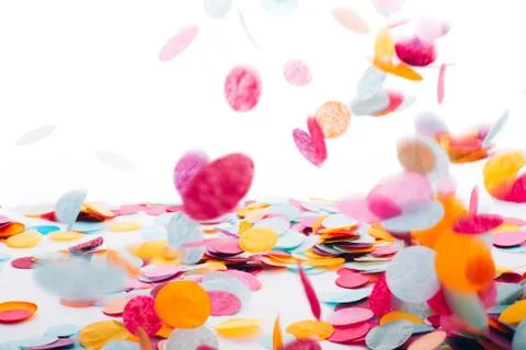 Multicolored round confetti is flying to the table. Stock Photos