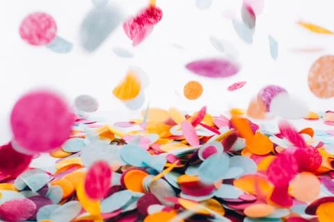 Multicolored round confetti is flying to the table. Stock Photos