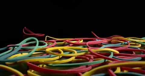 Multicolored Rubber bands falling on black surface. Products for all occasions Stock Footage 146795043