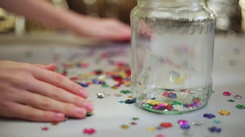 Multicolored sequins collecting to jar. Stock Footage 98313701