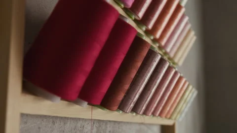 Multicolored Sewing Thread Bobbins on Wall Rack in Workshop Stock Footage 315771469