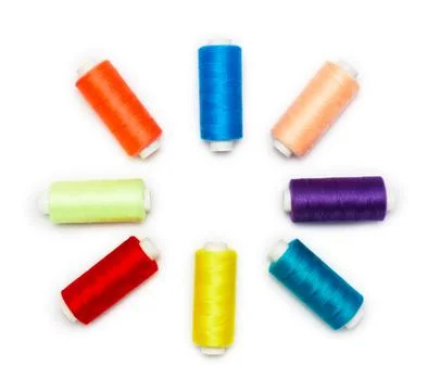 Multicolored sewing thread spools arranged in a circular pattern on a white b Foto stock