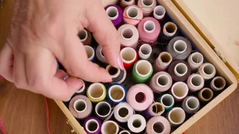 Multicolored sewing threads lie in wooden box. person body part hand folds Stock Footage 329282888