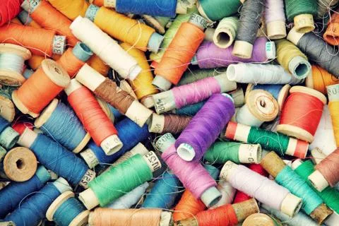 Multicolored sewing threads in spools as background. Stock Photos