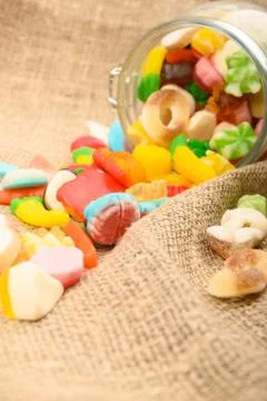 Multicolored shaped marmalade on a background of rough homespun fabric close- Stock Photos