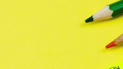 Multicolored sharp wooden colored pencils lie on a pastel yellow background with Stock Footage 158875134