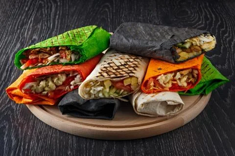 Multicolored shawarma in pita bread is cut and lies on a wooden surface. The  Stock-Fotos