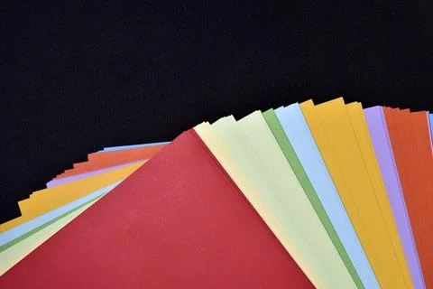 Multicolored sheets of paper on a black background. Colored office paper. A.. Foto stock