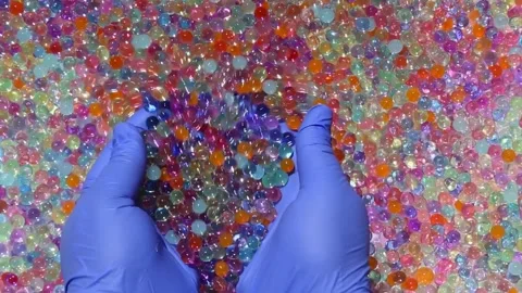 Multicolored shiny, small balls in the palms smoothly spill out against. part4. Stock Footage 277438234