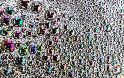 Multicolored soap foam bubbles on the surface of a puddle of water create a r Stock Photos