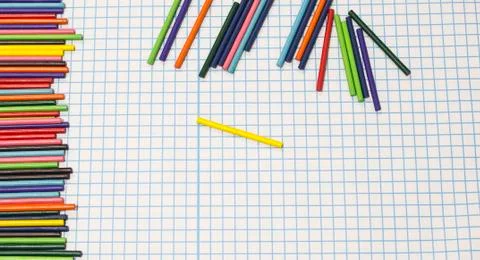 Multicolored sticks lay on a cellular background. Stock Photos