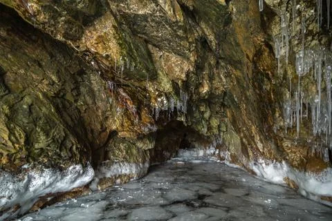 Multicolored stone cave in the cliff with icicles Stock Photos