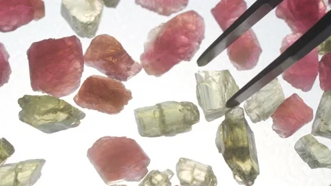 Multicolored stones on a white background close-up. Minerals and gems. Tweezers Stock Footage 157006839