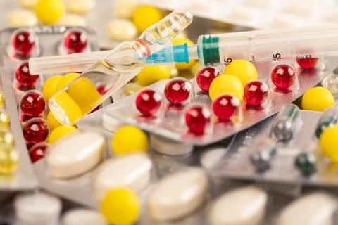 Multicolored tablets and capsules on the table. Ampoule and syringe for inj.. Foto stock