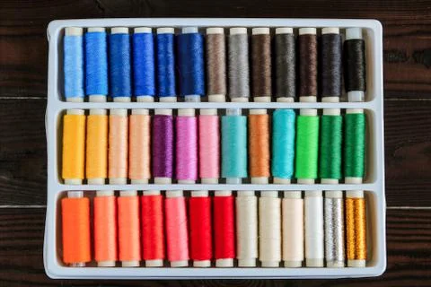 Multicolored thread for sewing in coils on a dark wooden surface top view Foto stock