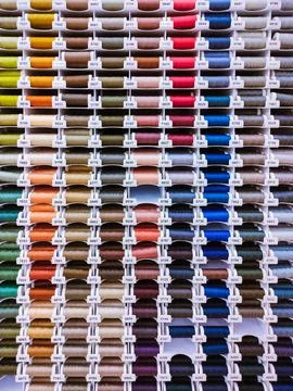 Multicolored thread spools in rows, sewing background Stock Photos