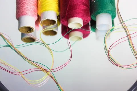Multicolored threads in the coils reflected on the surface of the mirror flat Stock Photos