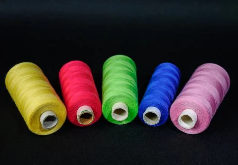Multicolored threads with a needle and scissors on a black background Foto stock