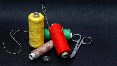 Multicolored threads with scissors on a black background Foto stock